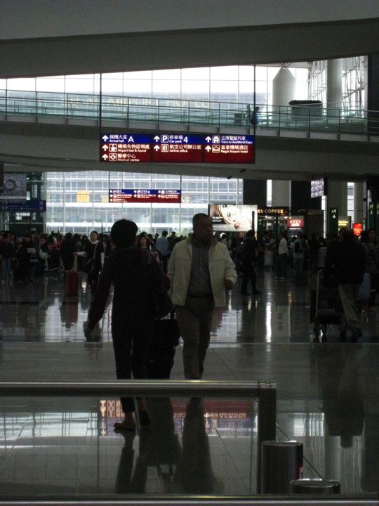 香港国際空港で藤村と待ち合わせ。金子に気付かず、さっそうと歩く藤村。